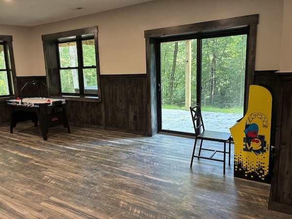 A room with a foosball table, a chair, and a large window with a view of trees.