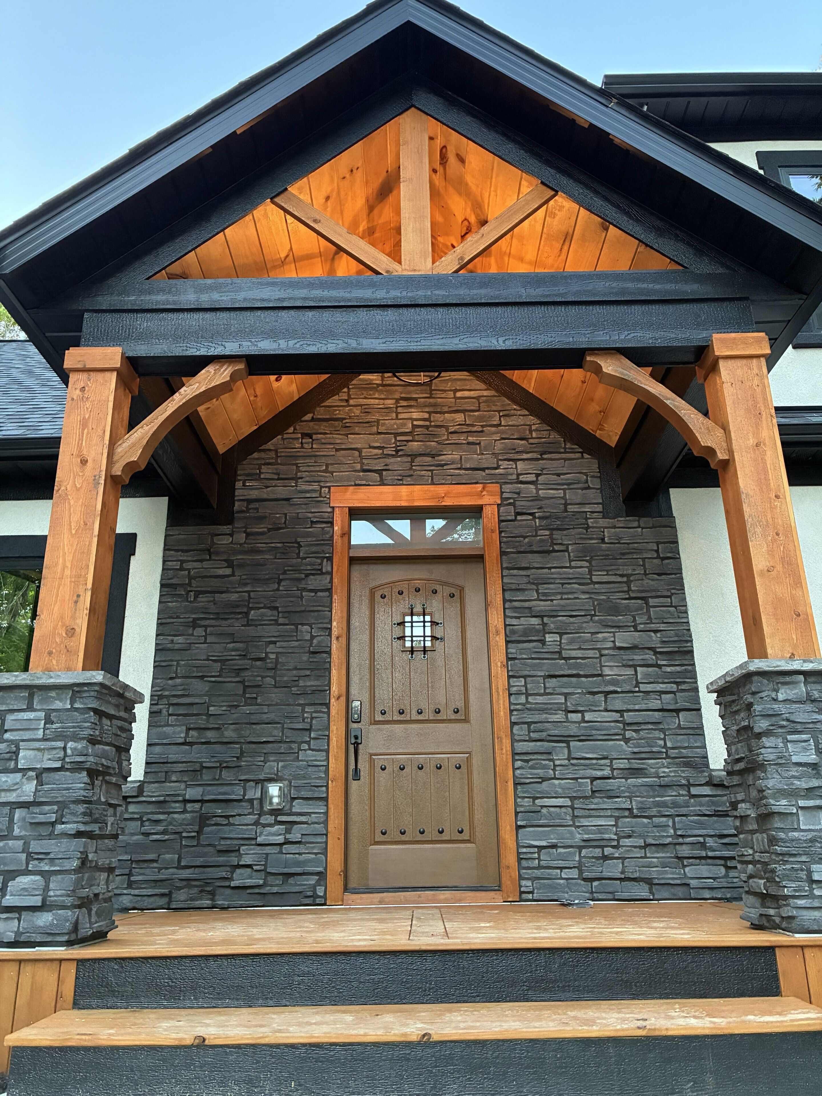 A building with a stone facade, a wooden door with a grid pattern, and a black roof.