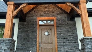 A building with a stone facade, a wooden door with a grid pattern, and a black roof. - The Wooded Obsidian Overlook cabin, with hot tub, games, and close to everything (Logan)
