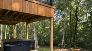 A wooden deck with a hot tub, a fire pit, and a stone fire pit. - The Wooded Obsidian Overlook cabin, with hot tub, games, and close to everything (Logan)