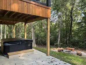 A wooden deck with a hot tub, a fire pit, and a stone fire pit.