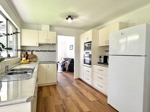 A modern kitchen with white cabinets, a stainless steel sink, and a refrigerator.