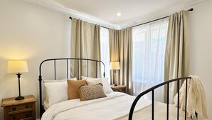 Ein Schlafzimmer mit einem Himmelbett, zwei Nachttischen und einem Fenster mit Vorhängen.