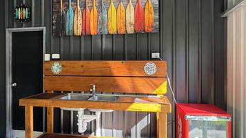 A wooden bench with a sink, a wall-mounted clock, and a row of painted oars.