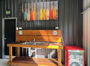 A wooden bench with a sink, a wall-mounted clock, and a row of painted oars.