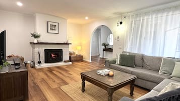 A living room with a fireplace, a sofa, a coffee table, and a television.