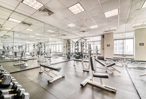 A spacious gym with various exercise equipment, large windows, and a mirrored wall. - Blueground | Kips Bay, pool, nr Empire State (New York)