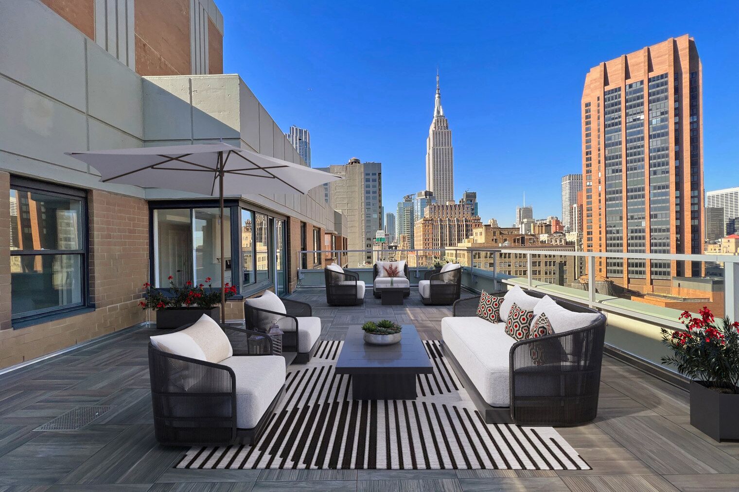 A rooftop terrace with outdoor seating, a view of the Empire State Building, and a cityscape in the background.