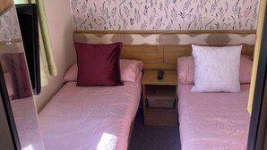 Un dormitorio con dos camas, cada una con una almohada y una mesita de noche.