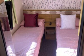 Ein Schlafzimmer mit zwei Betten, jedes mit einem Kissen und einem Nachttisch.