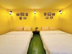Ein Zimmer mit zwei Betten, gelben Wänden und Wandleuchten.