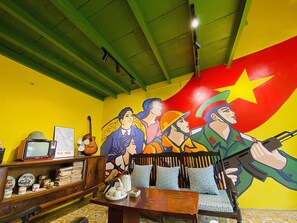 A room with a mural, a television, and a table with chairs.
