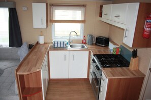 A compact kitchen with a sink, stove, and cabinets. - 8 Berth caravan at Butlins Skegness Pets friendly (Skegness)