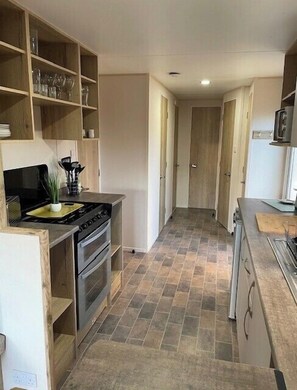 A narrow kitchen with a stove, oven, and cabinets. - 8 Berth caravan Butlins Skegness (Skegness)