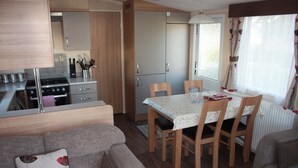 Un espai vital reduït amb petita cuina, taula de dinar i zona de seients.