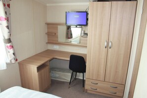 Ein kleines Schlafzimmer mit einem Holztisch, einem schwarzen Stuhl, einem Bett und einem Kleiderschrank.