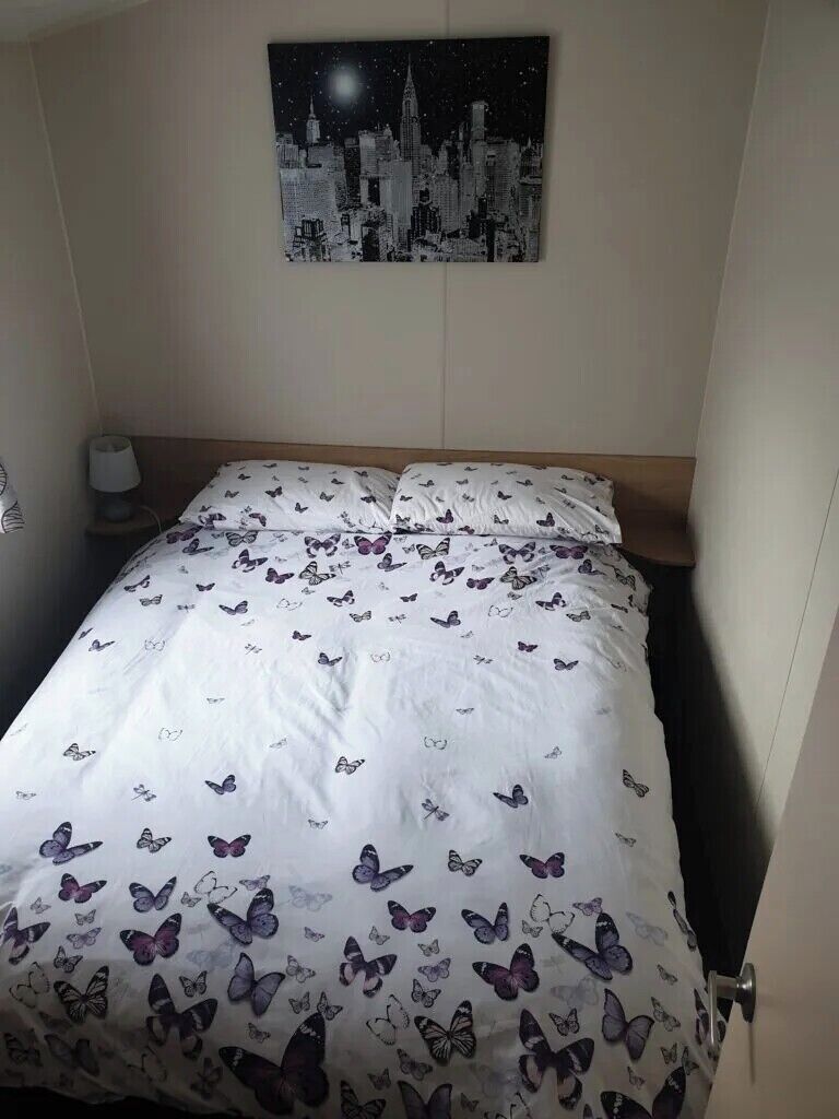 Une chambre d’hôtel avec un lit, une œuvre d’art représentant un paysage urbain nocturne accrochée au mur et une table de chevet avec une lampe.