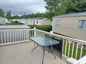 A deck with a table and chairs, surrounded by a white railing, in a mobile home park. - 8 berth caravan at Butlins Skegness (Skegness)
