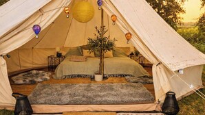 A cozy tent with a bed, pillows, a small table, and hanging lanterns. - Countryside Avon Escape for Two (Pewsey)