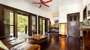 A spacious living area with a leather sofa, a wooden coffee table, and a ceiling fan.