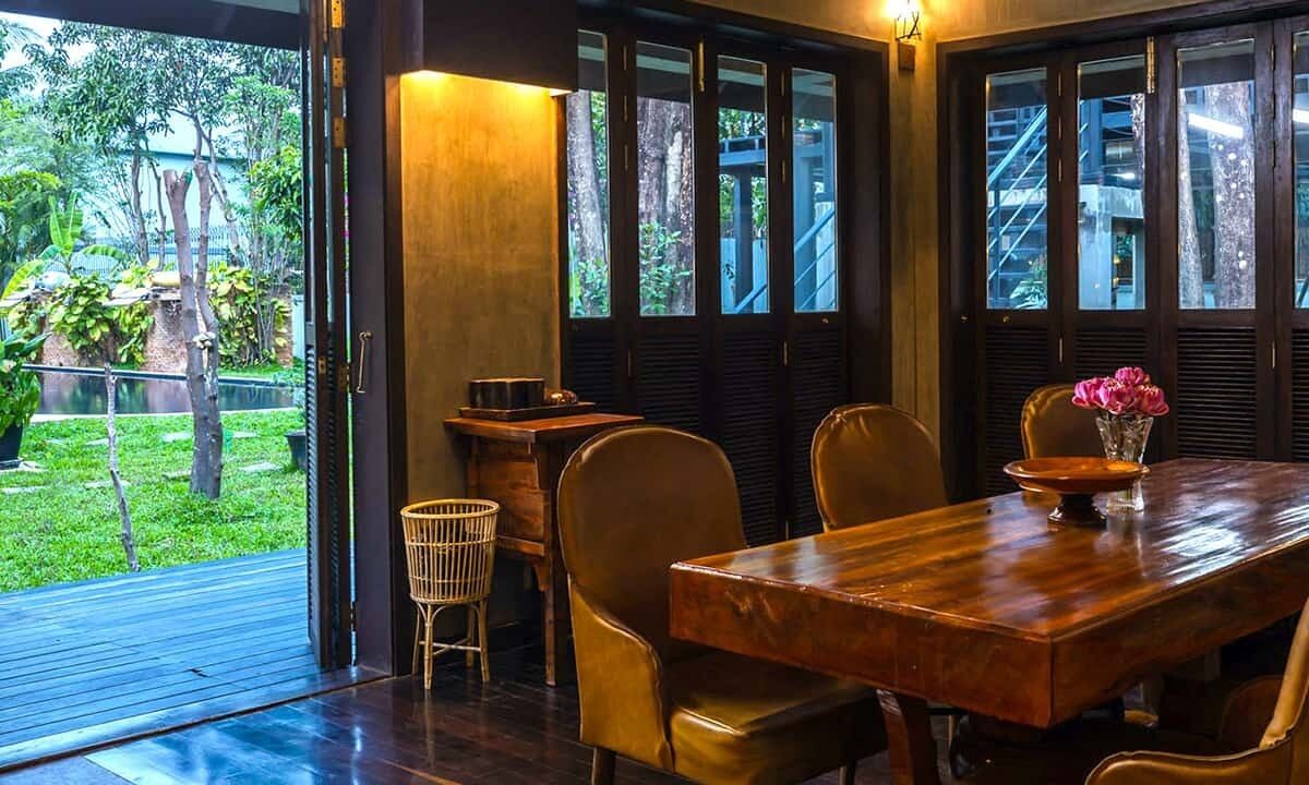 A dining area with a wooden table, chairs, and a vase of flowers.