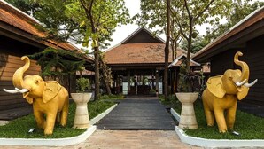 A pathway leading to a building with a tiled roof, flanked by elephant statues on either side.