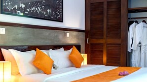 A hotel room with a bed, pillows, a nightstand, a lamp, and a wardrobe.