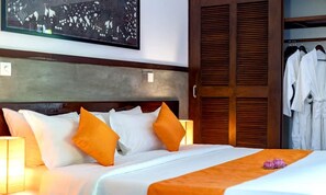 Une chambre d’hôtel comprenant un lit, des oreillers, une table de chevet, une lampe et une armoire.