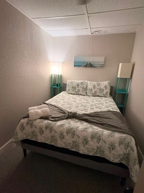 Ein Schlafzimmer mit einem Bett, zwei Nachttischlampen, einem Bild an der Wand und einem Fenster.