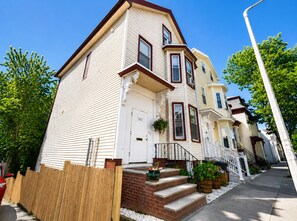 A row of townhouses with a brick entrance, a white door, and a small porch with steps.