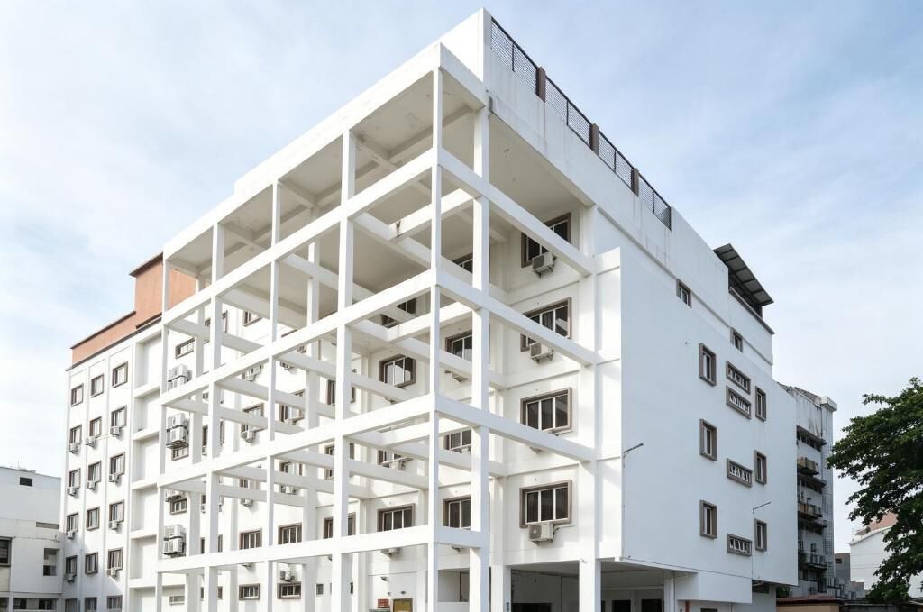 A multi-story building with a grid-like facade, multiple balconies, and air conditioning units.