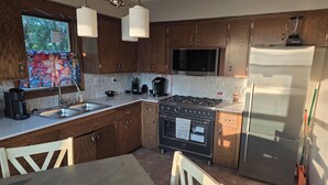 A kitchen with wooden cabinets, a stainless steel refrigerator, a stove, and a microwave. - Spacious 4-bedroom house in tranquil Farmington with yard and fire pit. (Farmington)