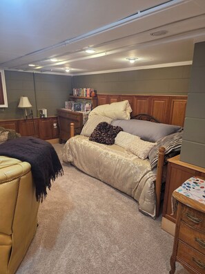 A bedroom with a bed, a chair, a nightstand, a lamp, and a bookshelf. - Spacious 4-bedroom house in tranquil Farmington with yard and fire pit. (Farmington)