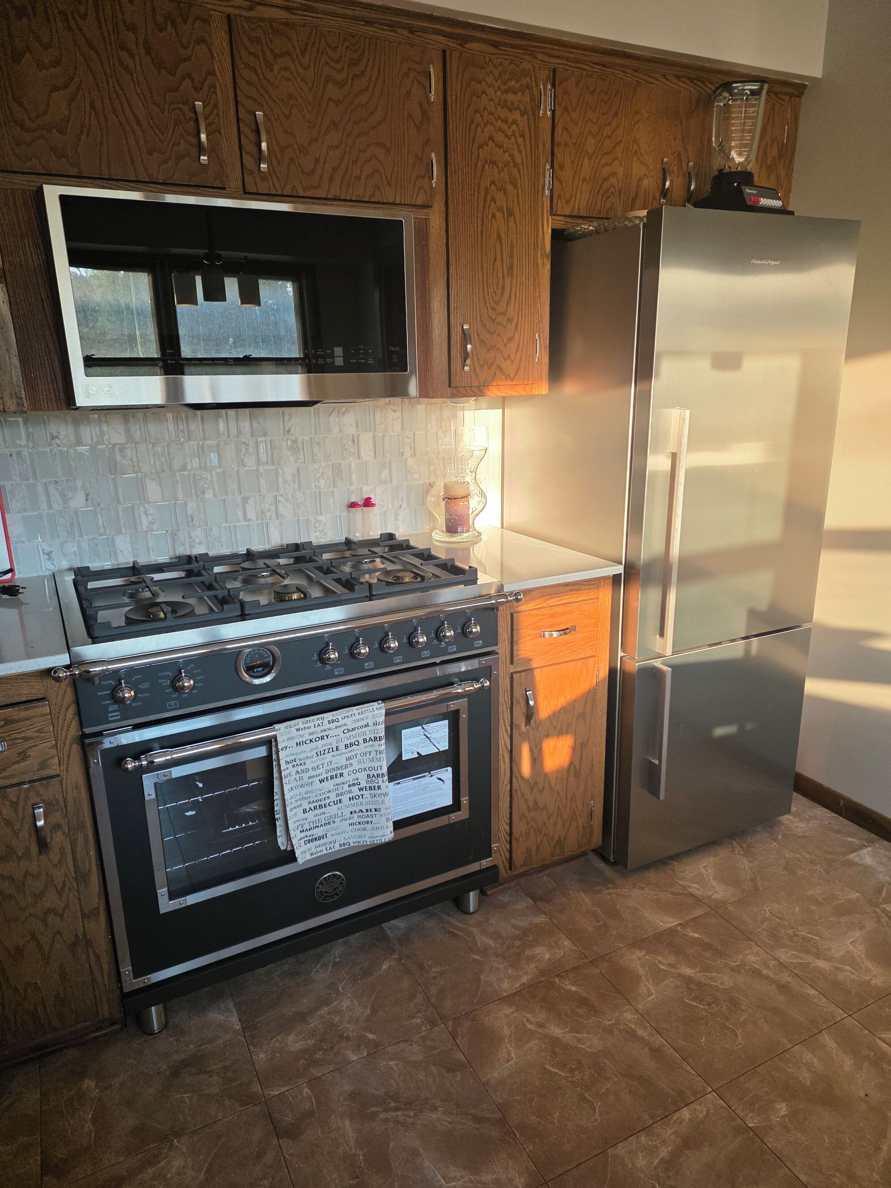 A kitchen with wooden cabinets, a stainless steel refrigerator, a gas stove, and a built-in oven.