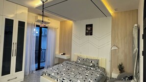 A modern bedroom with a bed, wardrobe, and a small seating area. - Bunny House (Da Nang)