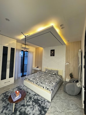 Une chambre moderne avec un lit, une armoire et un petit coin salon.
