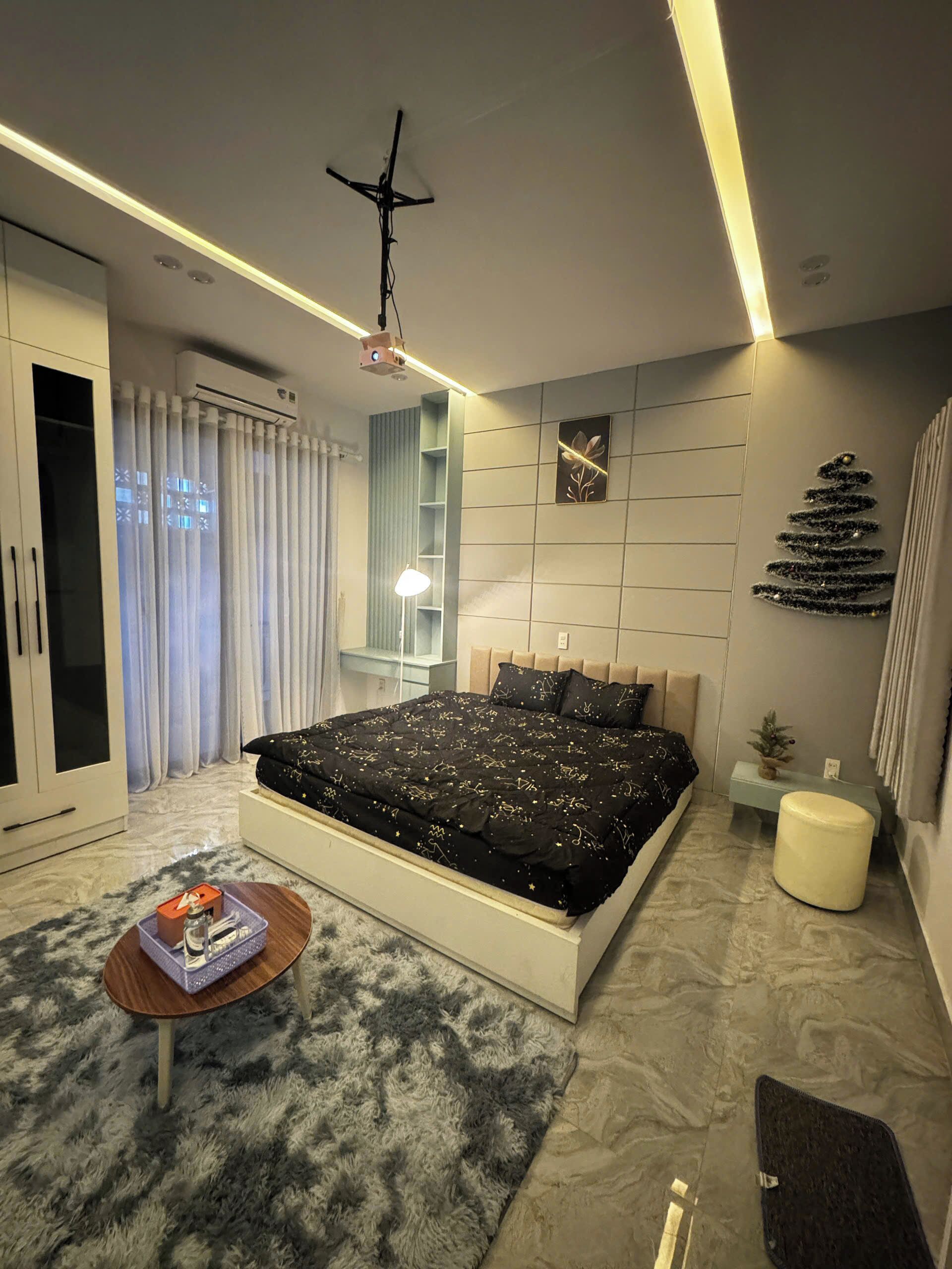 A modern bedroom with a large bed, a bedside table, a lamp, and a decorative wall piece.