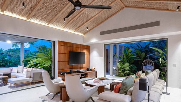 A modern living room with a flat-screen TV, comfortable seating, and large windows overlooking greenery. - Villa Ceiba - Selva Punta Mita (Punta de Mita)