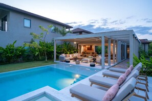 Ein modernes Haus mit Swimmingpool, Sitzbereich im Freien und einer überdachten Terrasse.