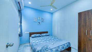 Une chambre à coucher comprenant un lit, une armoire, un ventilateur de plafond et des œuvres d’art accrochées au mur.