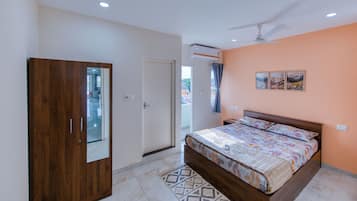 A bedroom with a bed, a wardrobe, an air conditioning unit, and a ceiling fan.
