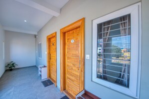 Un corridoio con due porte in legno e un'ampia finestra.