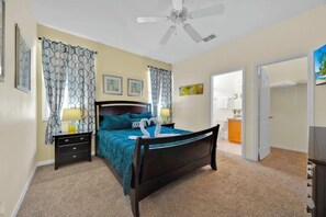 A bedroom with a bed, nightstands, a ceiling fan, and a door leading to a bathroom. - 5BR Disney Home, Private Pool, Spa & PS5 Game Loft (Davenport)