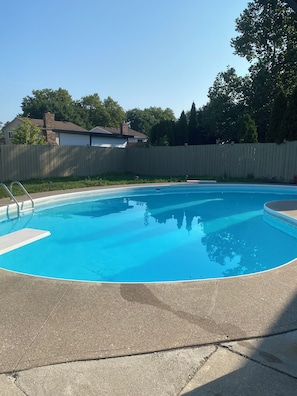 A swimming pool with a wooden fence and a clear blue sky in the background.