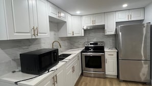 A kitchen with white cabinets, a stainless steel refrigerator, a microwave, and a stove. - Cozy 2-bedroom house in fantastic Windsor with AC (Windsor)