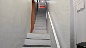 A staircase with white steps and a handrail, leading to an orange door at the top.