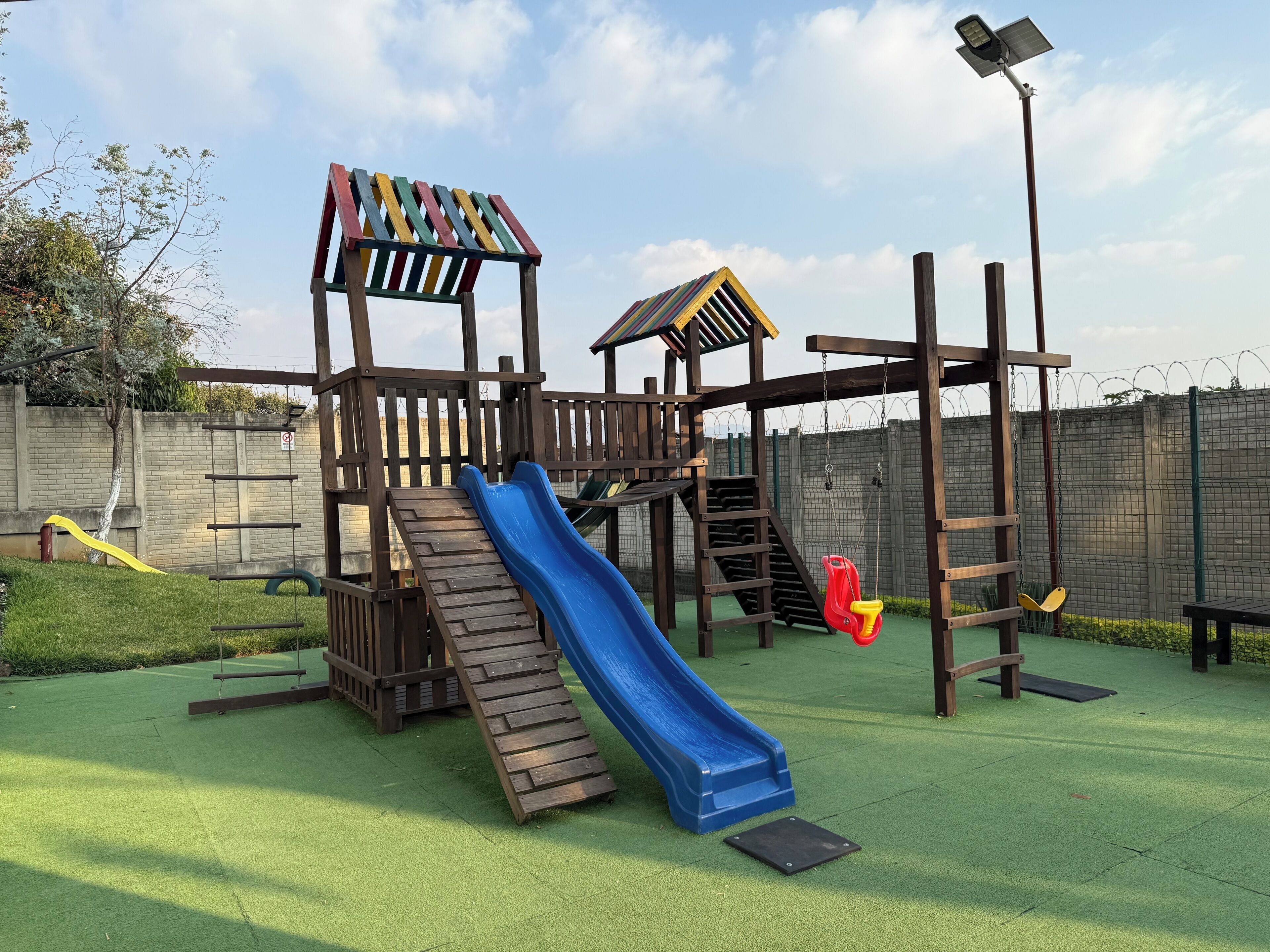 Un parque infantil con tobogán, estructuras para escalar y columpios.