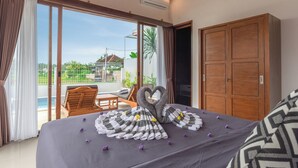Quarto de hotel com uma cama, guarda-roupa de madeira, varanda com piscina e vista para o verde lá fora.