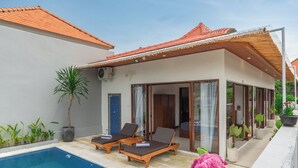 Uma villa moderna com piscina, espreguiçadeiras e um terraço coberto.
