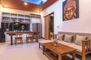 Un espace de vie moderne comprenant un coin repas, un canapé et un tableau représentant un Bouddha.